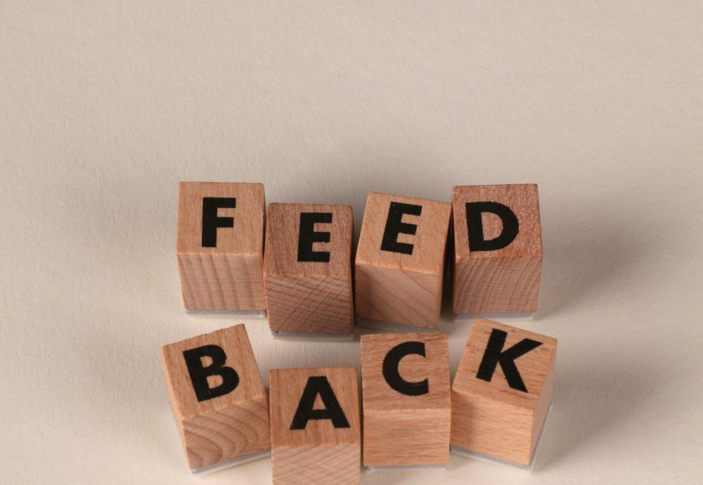 Wooden blocks forming the word 'Feedback' against a neutral beige background, conveying communication or review concept.